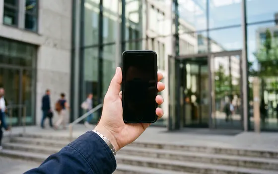 Anfrage per Smartphone vor einem Bürogebäude in Köln
